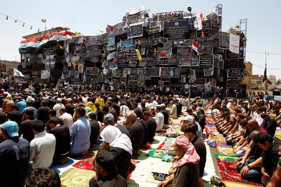 Mostly shi'ite Muslims attend Friday prayers during Eid al-Fitr as they mark the end of the fasting month of Ramadan, at the site of a suicide car bomb attack over the weekend at the shopping area of Karrada, in Baghdad