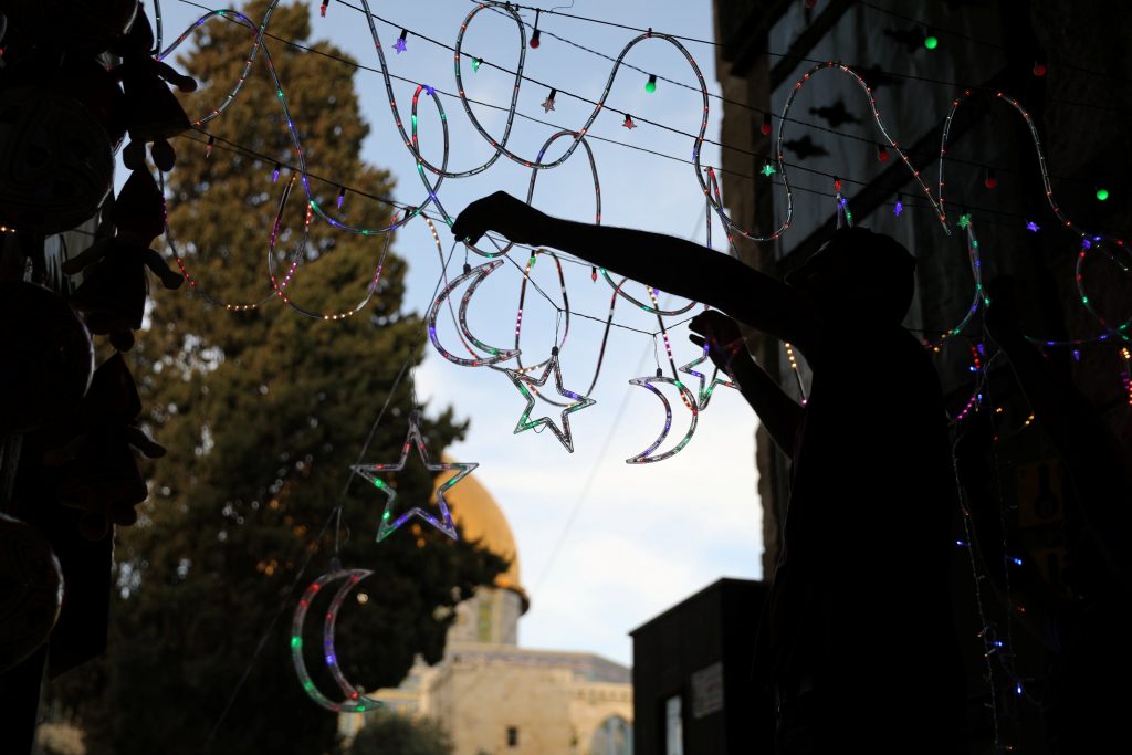 A Palestinian man hangs decorations at the entrance to the compound known to Muslims as al-Haram al-Sharif and to Jews as Temple Mount, in Jerusalem's Old City May, 17, 2017. REUTERS/Ammar Awad